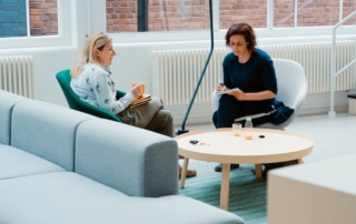 two woman sits on sofa chairs inside house