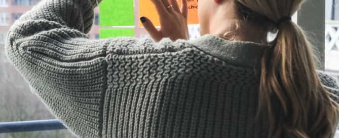 woman in gray sweater holding smartphone